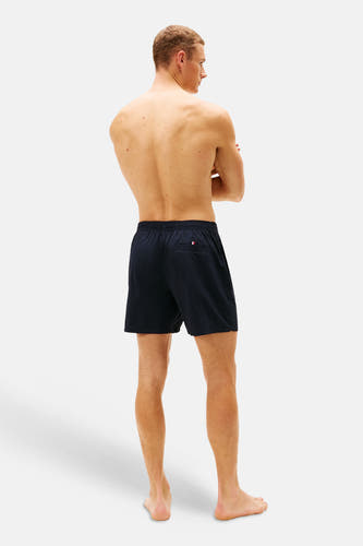 Blauwe zwemshort van TOMMY JEANS, gezien van achteren, met een kleine logo-vlag op de achterzak.