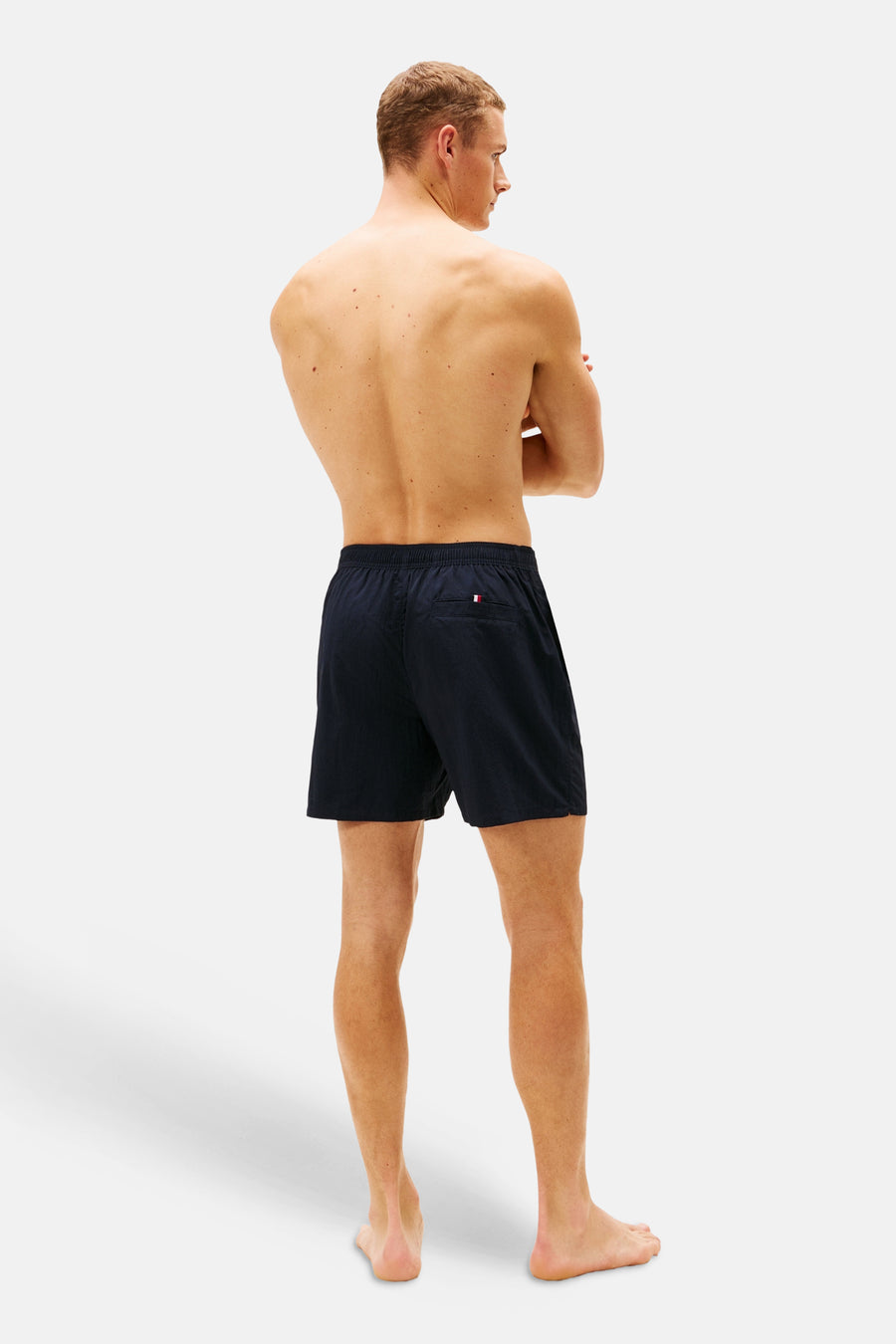 Blauwe zwemshort van TOMMY JEANS, gezien van achteren, met een kleine logo-vlag op de achterzak.