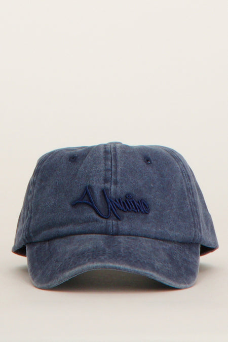 Blauwe pet van Unwind met geborduurd logo op de voorkant.
