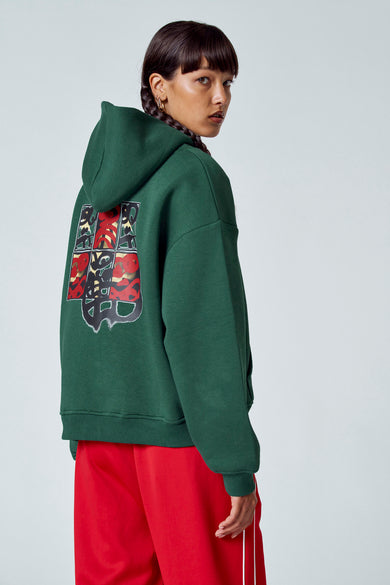 Pull-over vert avec capuche Unwind, avec poche broiquée, associé à un short de jogging rouge.