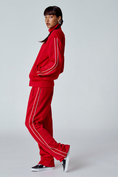Rood gilet van Unwind, met ecru details en witte strepen, gedragen met bijpassende broek en zwarte sneakers.
