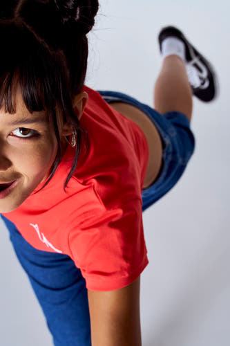 Rood T-shirt met korte mouwen van Unwind, gedragen met een blauwe broek en zwarte schoenen, vanuit vogelperspectief.
