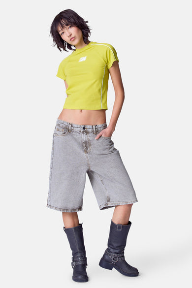 T-shirt vert avec manches courtes d'Unwind, avec un logo sur la poitrine et des bretelles blanches.