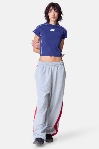 Blauw T-shirt met korte mouwen van Unwind, met witte bies aan de zijkant en gedragen met grijze joggingbroek.
