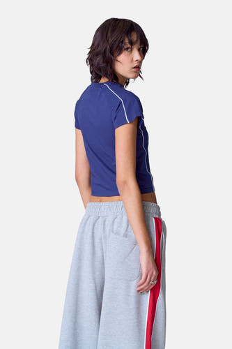 Blauw T-shirt met korte mouwen van Unwind, gezien van achteren, met witte strepen en gedragen met grijze joggingbroek.
