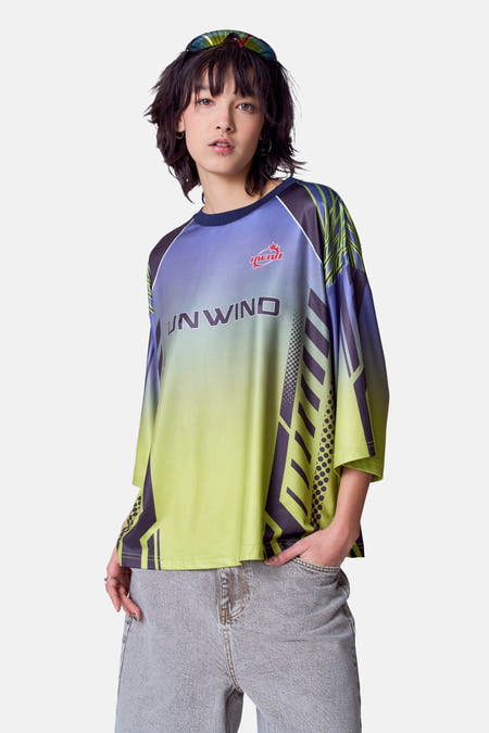 Groen T-shirt met korte mouwen van Unwind, met kleurverloop en geometrische patronen, gedragen met een grijze jeans.
