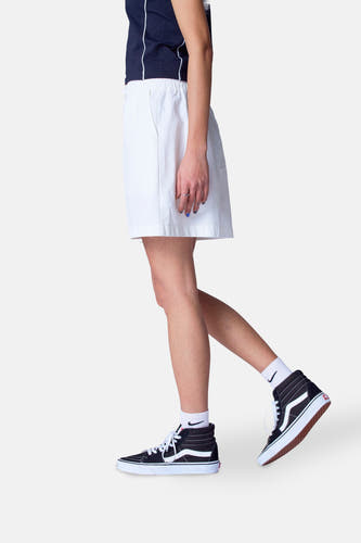 Witte short van Unwind, gecombineerd met een donkerblauw shirt en hoge Vans-schoenen met witte sokken.
