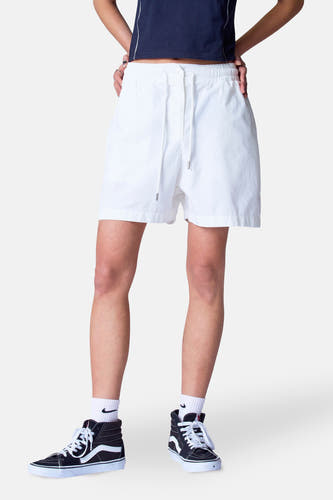 Witte short van Unwind, met trekkoord en gedragen met zwarte hoge sneakers en witte sokken.
