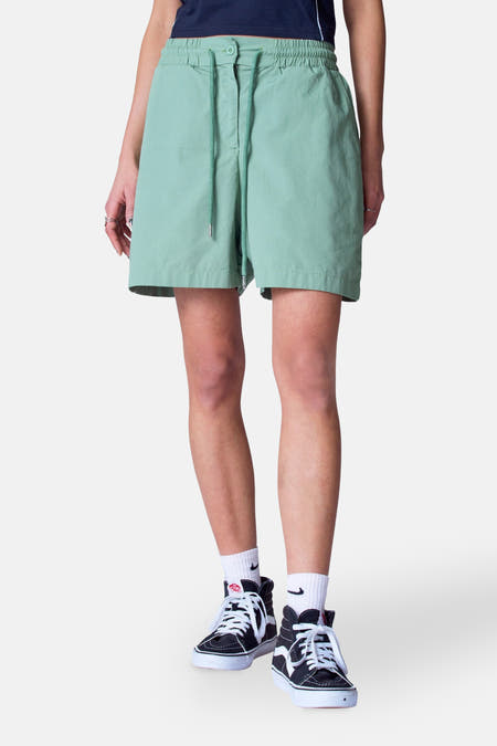 Groene short van Unwind, met trekkoord, gecombineerd met witte sokken en hoge sneakers.
