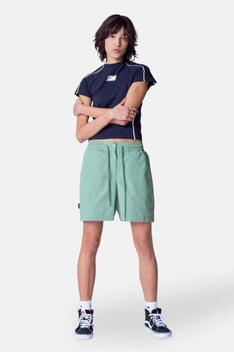 Groene short van Unwind, met trekkoord en gedragen met een donkerblauw shirt en zwarte hoge sneakers.
