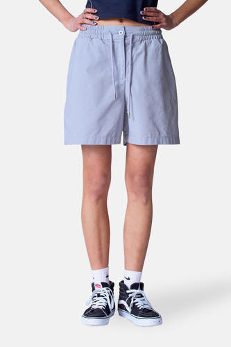 Grijze short van Unwind, met trekkoord en gedragen met witte sokken en hoge sneakers.
