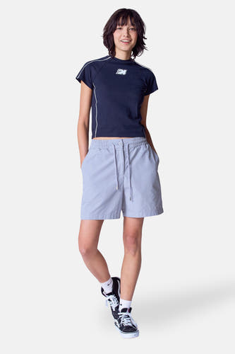 Grijze short van Unwind, met een trekkoord en gedragen met een donkerblauwe top en hoge sneakers.
