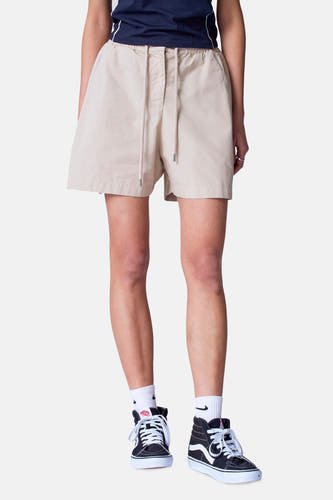 Beige short van Unwind, met trekkoord en gedragen met zwarte sneakers en witte sokken.
