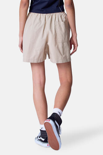 Beige short van Unwind, met achterzak en gedragen met zwarte hoge sneakers en witte sokken.

