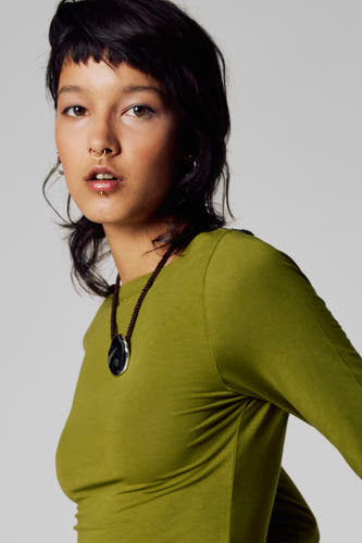T-shirt vert avec manches longues d'Unwind, porté avec une chaîne à cintre, sur un modèle.
