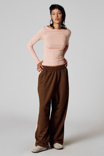 T-shirt rose à manches longues d'Unwind, associé à un pantalon marron et des chaussons beige.