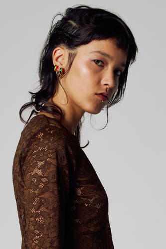 T-shirt marron à manches longues d'Unwind, avec des détails sur les bords et une femme avec des piercing.