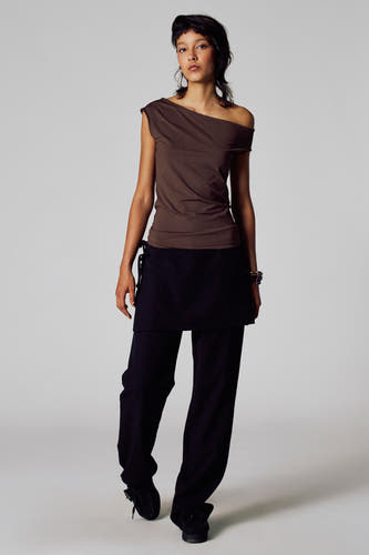 Bruin T-shirt met korte mouwen van Unwind, gedragen met een zwarte rok en pantalon.
