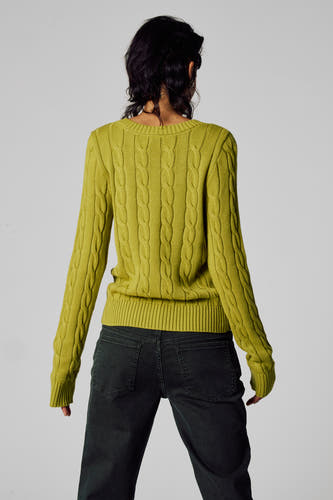 T-shirt V-hals vert de Unwind, avec un motif côtelé et des manches longues, porté avec un pantalon foncé.