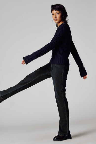 Blauwe trui met V-hals van Unwind, met kabelpatroon en lange mouwen, gedragen met een donkere jeans en schoenen.

