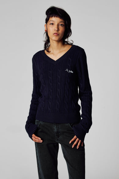 Blauwe V-hals trui van Unwind, met kabelpatroon en een klein logo op de borst.
