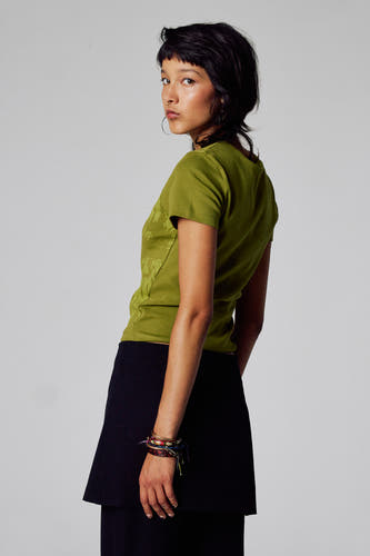 T-shirt vert avec manches courtes d'Unwind, avec un motif subtil, associé à une jupe noire et des bracelets.