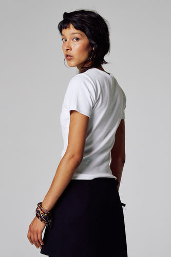T-shirt blanc à manches courtes d'Unwind, porté avec une jupe noire et des bracelets.