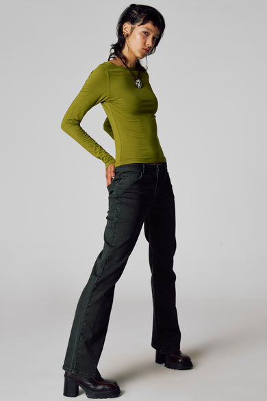 Groene T-shirt met lange mouwen van Unwind, gecombineerd met donkere jeans en bruine schoenen met hak.