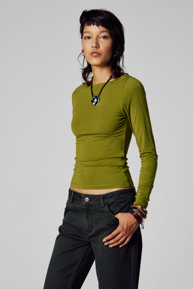 Groene t-shirt met lange mouwen van Unwind, met een ronde hals, gecombineerd met een ketting en corduroy broek.

