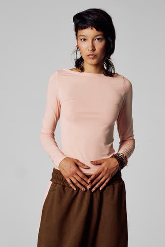 T-shirt rose à manches longues d'Unwind, à manches longues, associé à un pantalon marron.