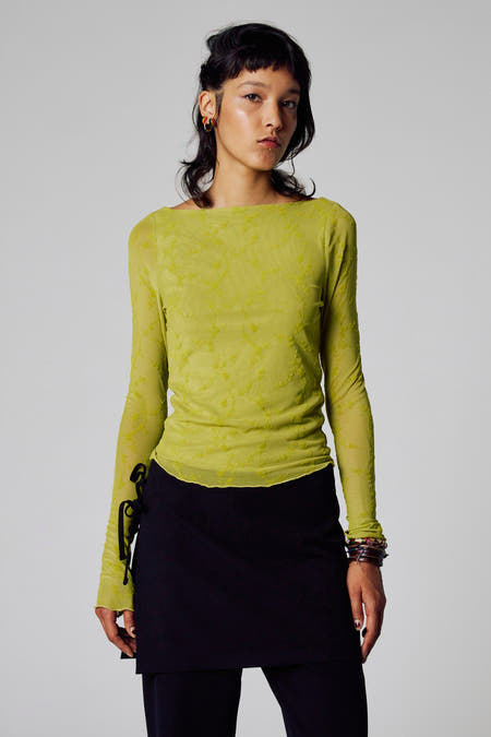 Groene T-shirt met lange mouwen van Unwind, met patroon en gedragen met een zwarte rok en armbanden.
