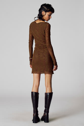 Robe brune à longues manches de Unwind, avec un motif floral et portée avec des bottes noires hautes.
