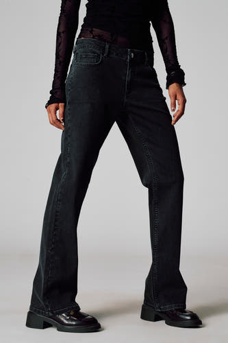 Grijze colorbroek van Unwind, met een losse pasvorm en gecombineerd met een doorschijnende top en zwarte loafers.
