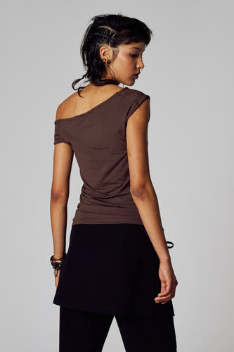 Bruin T-shirt met korte mouwen van Unwind, met één blote schouder, gecombineerd met zwarte rok en legging.