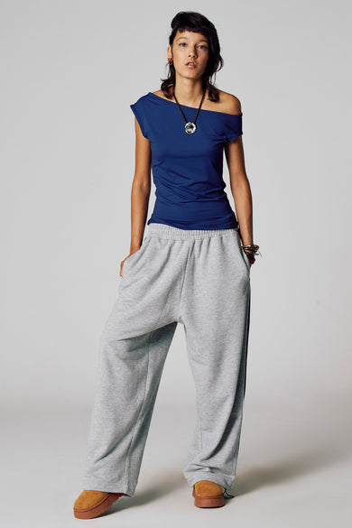 T-shirt bleu à manches courtes d'Unwind, porté avec une chaîne et un pantalon de jogging gris, avec une coupe décontractée.