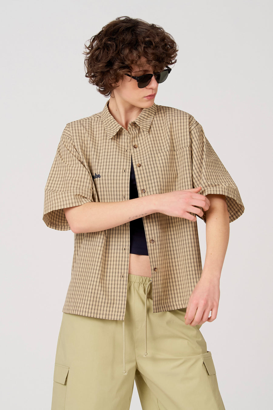Chemise beige à manches courtes d'Unwind, à carreaux et associée à un pantalon kaki.