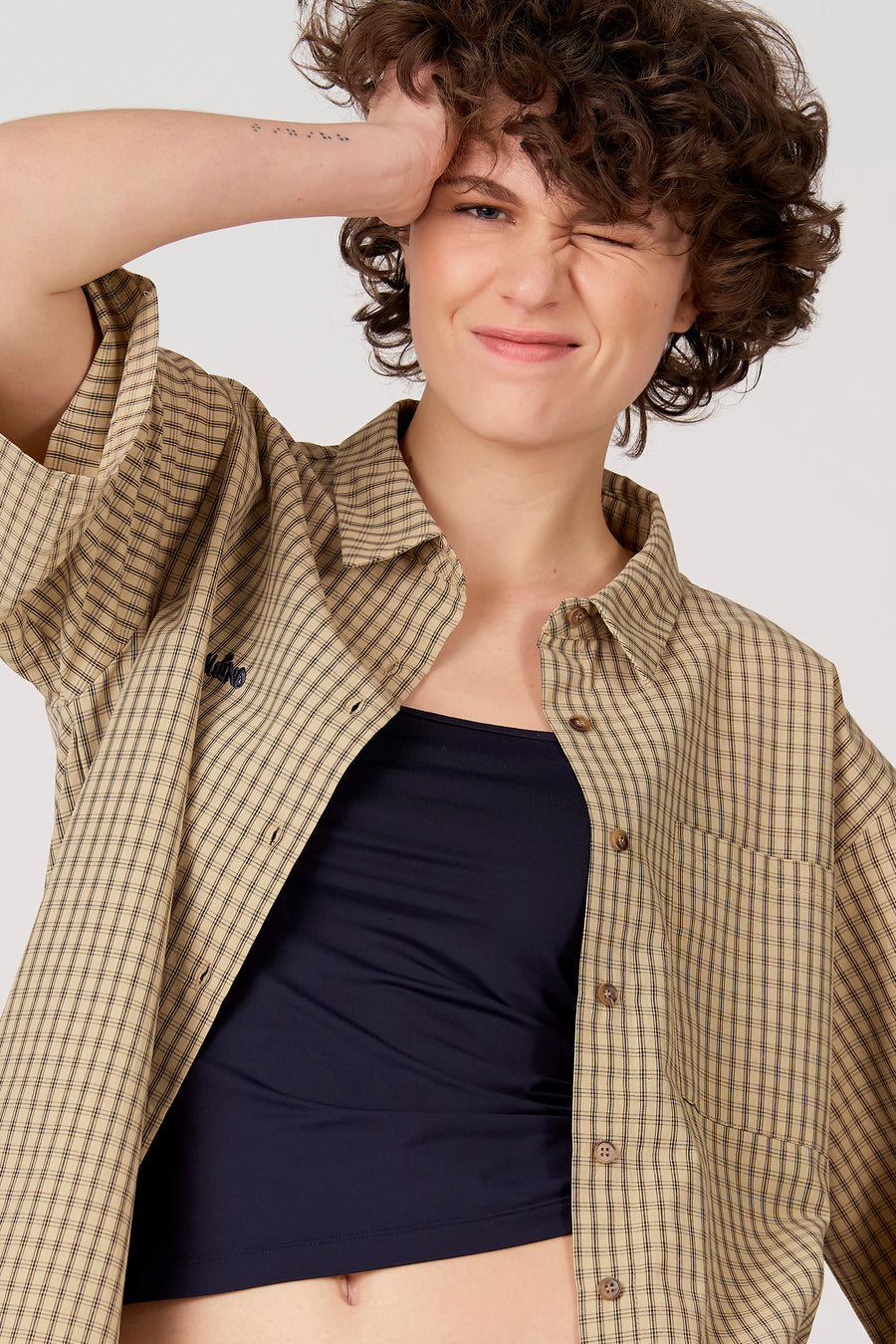 Chemise beige à manches courtes d'Unwind, à motif à carreaux et avec un haut noir en dessous.