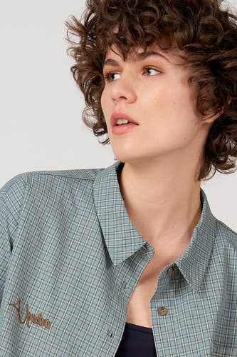Chemise bleue à manches courtes d'Unwind, avec un motif à carreaux et un logo brodé.