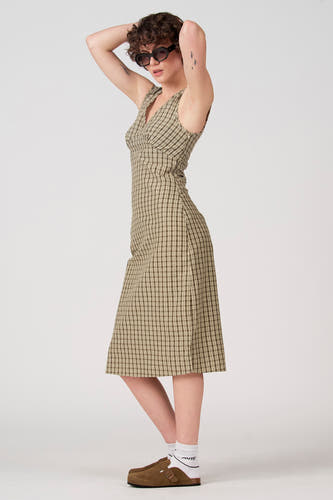 Robe sans manches verte d'Unwind, à motif à carreaux et portée avec des mules marron et des chaussettes blanches.
