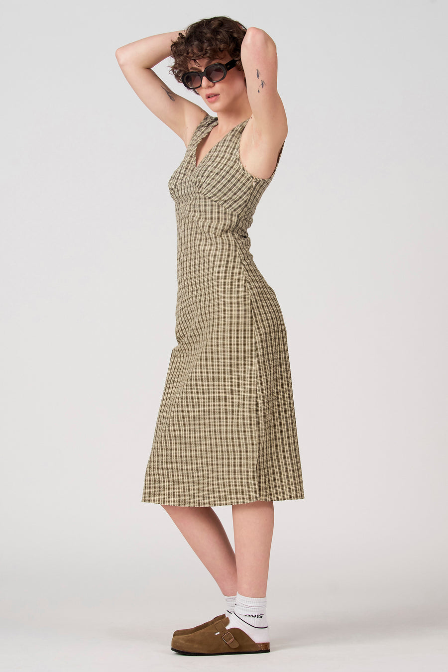 Robe sans manches verte d'Unwind, à motif à carreaux et portée avec des mules marron et des chaussettes blanches.
