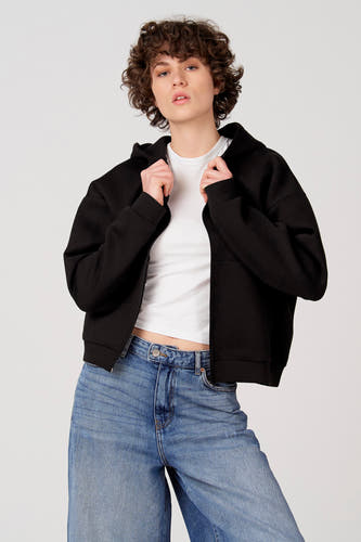 Gilet noir d'Unwind, porté sur un t-shirt blanc et un jean bleu.