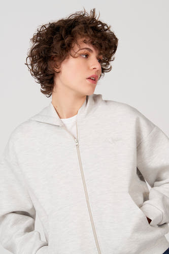 Gilet gris d'Unwind, avec fermeture éclair et capuche, combiné avec un t-shirt blanc.