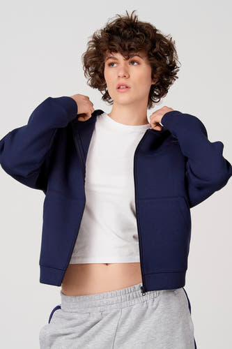 Blauw vest van Unwind, gedragen met een wit T-shirt en een grijze joggingbroek.