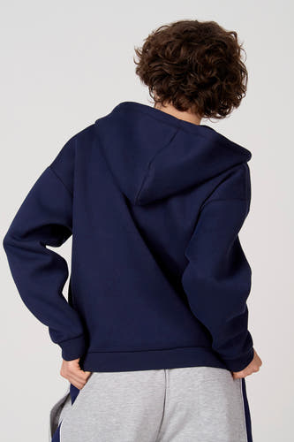 Blauw Unwind gilet, rugzijde gezien, met capuchon en grijze joggingbroek.
