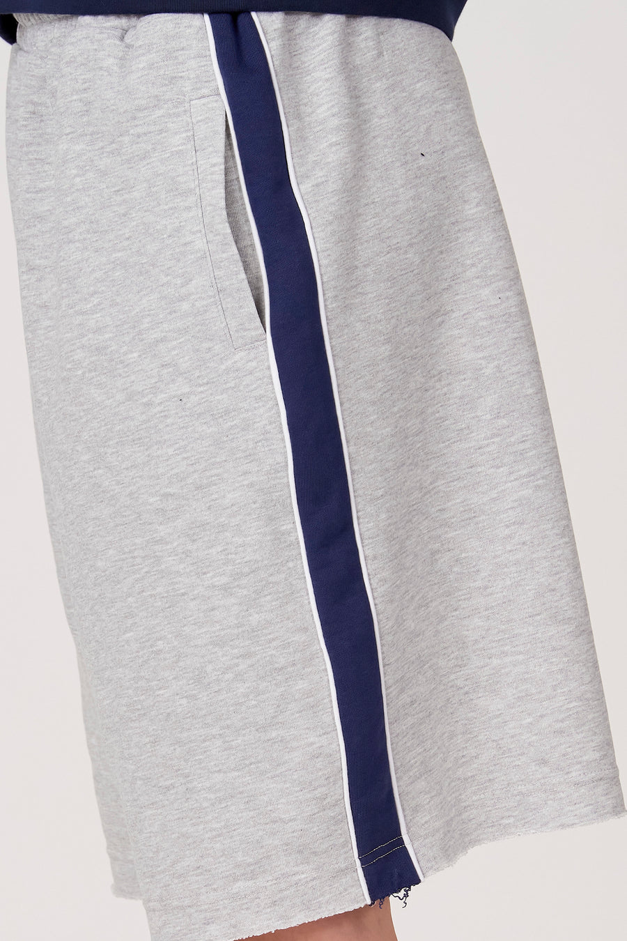 Short gris d'Unwind, avec une rayure bleu marine et un ourlet effiloché.