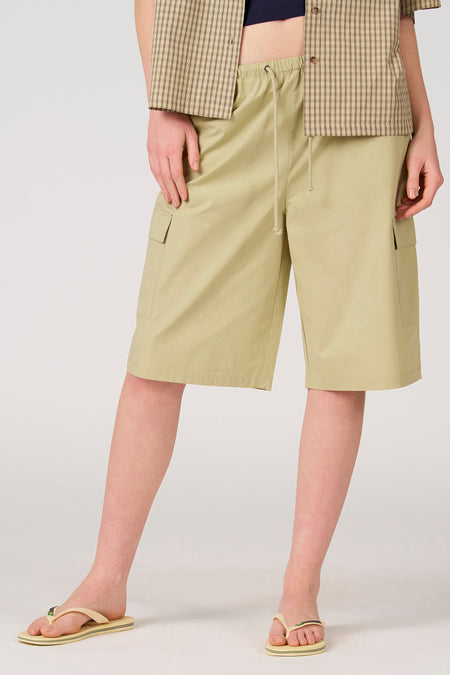 Short vert clair d'Unwind avec poches arrière plaquées et poches cargo, porté avec une chemise à carreaux et des tongs, vue arrière.