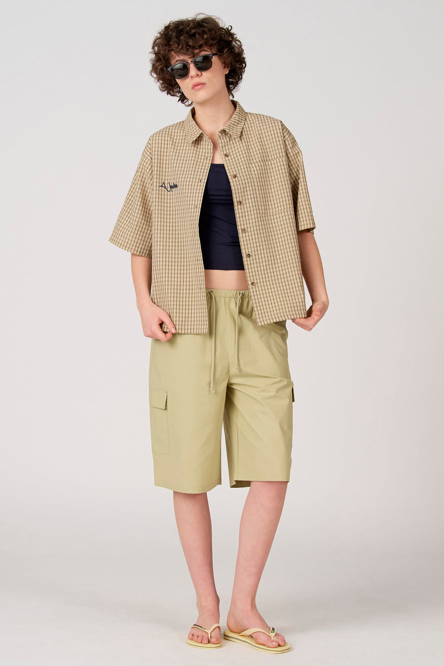 Short cargo vert de Unwind avec cordon de serrage, stylé avec une chemise à carreaux ouverte.