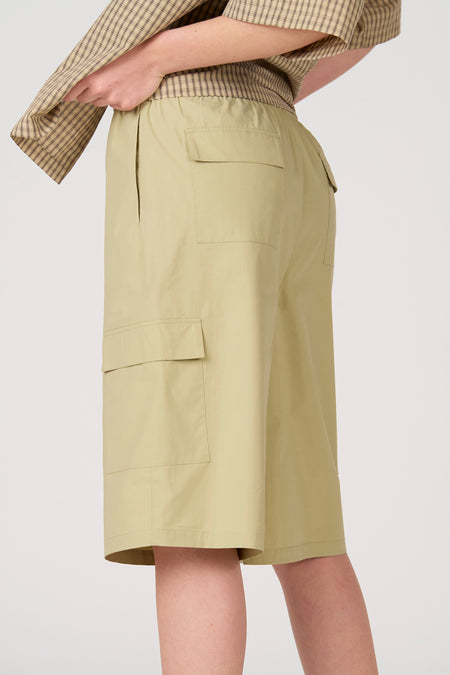 Lichtgroene cargo short van Unwind met elastische tailleband, steekzakken en klepzakken, gedragen met geruit overhemd.