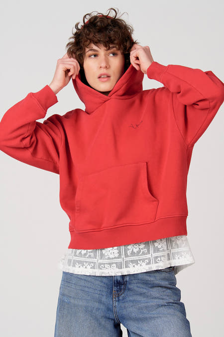 Rode sweater met kap van Unwind, met buidelzak en gecombineerd met kanten top en spijkerbroek.