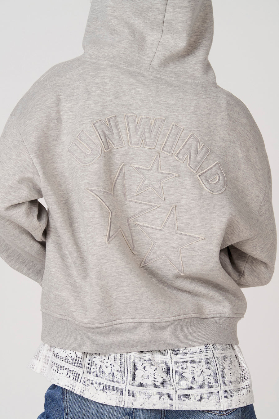 Sweat à capuche gris d'Unwind, avec texte brodé et étoiles dans le dos.
